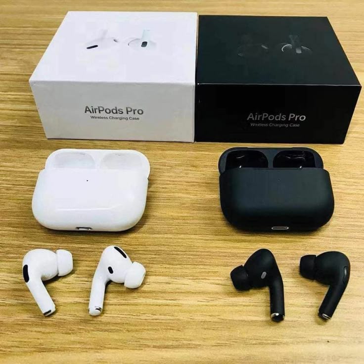 AirPods Pro with white and black charging cases on a wooden surface